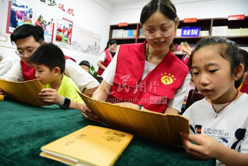 2020年7月19日,在江苏省镇江市金江社区农家书屋,乐动平台·(中国)官方网站志愿者在指导小朋友诵读经典诗文。